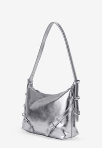 Bolso de hombro plateado metálico con textura suave, forma curvada y correa ajustable con acentos decorativos de hardware.