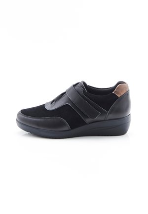 Zapato casual negro con tiras de velcro, parte superior de ante y cuero, acento marrón en el talón y suela baja tipo cuña.