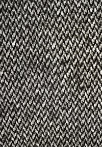Texturiertes schwarz-weißes Fischgrätgewebe mit einem Zickzackmuster und einer weichen, leicht flauschigen Oberfläche.