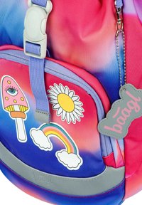 Zaino multicolore con un design a gradiente rosa e blu, decorato con adesivi di un ghiacciolo, una margherita, un arcobaleno e un'etichetta di marca.