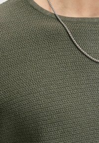 Close-up of olive green textured knit sweater with a silver chain necklace draped across the chest.