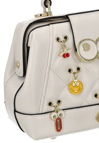 Bolso blanco acolchado con ribete negro, herrajes dorados y encantos divertidos que incluyen una cara sonriente, cerezas y un personaje caricaturesco.