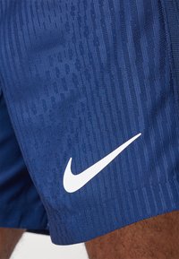 Marineblauwe sportshorts van Textiel met structuur, voorzien van verticale strepen en een prominent wit Nike-logo aan de onderzijde.