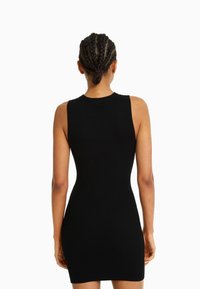 Robe sans manches noire à côtes avec une silhouette ajustée, un col haut et un ourlet au niveau du genou. Présente un tissu texturé et une forme légèrement moulante.