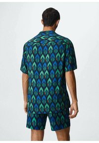 Monivärinen lyhythihainen paita ja shortsit, joissa on geometrinen nuolikuosi sinisen, vihreän ja punaisen sävyissä tummalla taustalla.