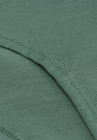 Grön tyg med en slät textur, med en ribbad söm. Materialet verkar lätt och har en svag glans.