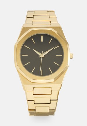 Montre-bracelet en métal doré avec cadran noir, index et aiguilles dorés, et bracelet à maillons affichant l'heure 10:10:30.