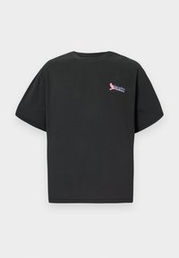 Zwarte katoenen t-shirt met korte mouwen, voorzien van een kleurrijk "Paradiso Airlines" logo op de linkerborst. Standaard crew neck ontwerp.