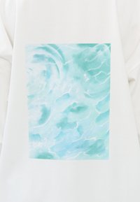 Wit stof met een vierkant blauw waterpatroon, waarin lichte en donkere aqua tinten zijn te zien, met zachte golftextures en witte accenten.