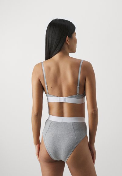 Grå sømløs bralette og høyt liv undertøy, med tynne stropper, elastisk midjebånd, glatt tekstur og minimalisk design.