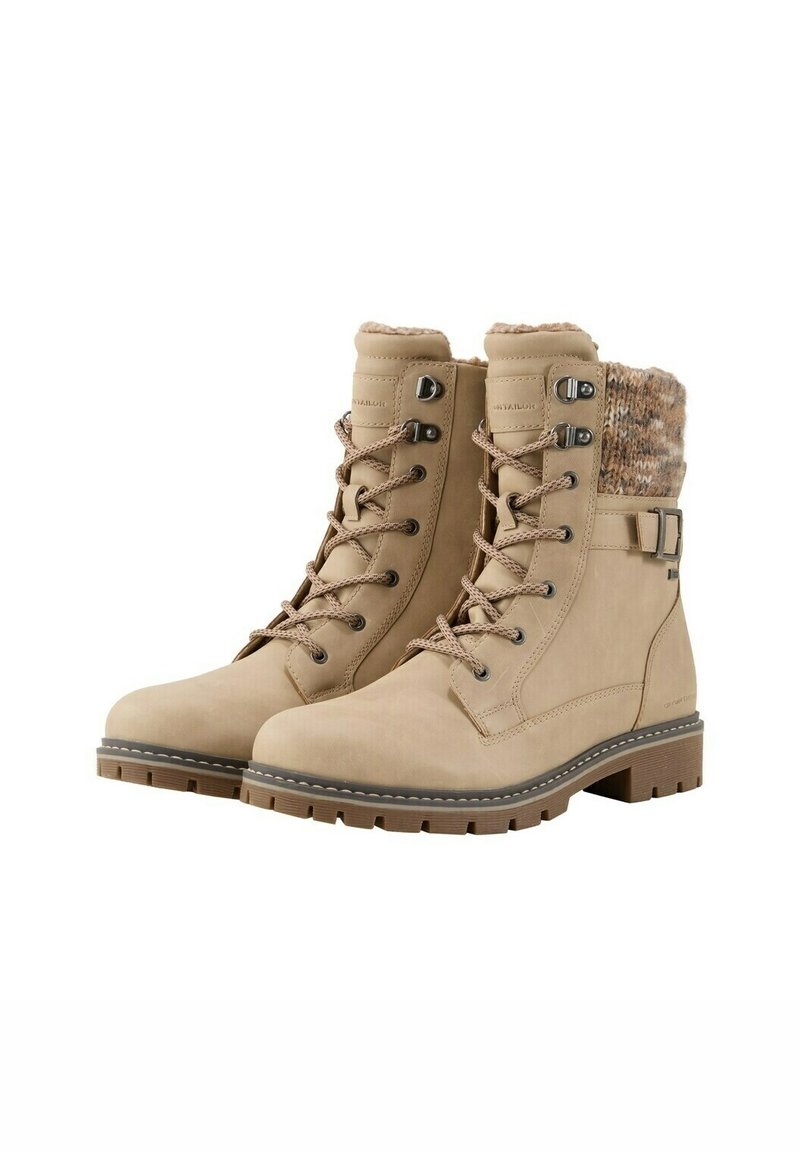 Botas de tobillo beige con cordones en la parte delantera, cuello de punto texturizado, suela de goma sólida y acento con hebilla lateral, que presentan detalles de textura dual y costuras.