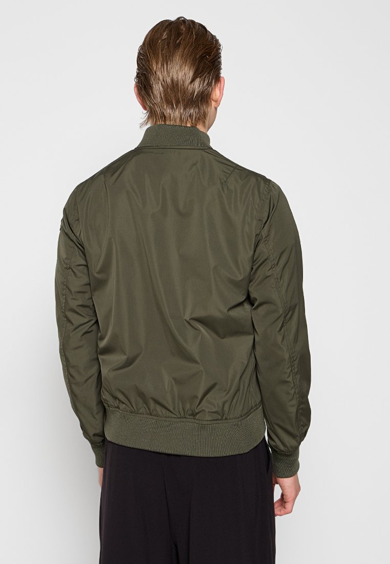 Veste bomber vert olive avec une texture lisse et brillante, des poignets et une taille côtelés, présentant une silhouette droite et des détails cousus.