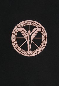 Czarna tkanina z okrągłym, jasnoróżowym emblematem. Emblemat przedstawia skrzydlatą postać z wyciągniętymi ramionami, otoczoną wzorami geometrycznymi.