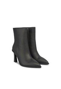 Botas de tobillo de cuero negro con punta afilada, textura suave y cremallera lateral. Presentan un tacón alto estructurado para mayor estabilidad.