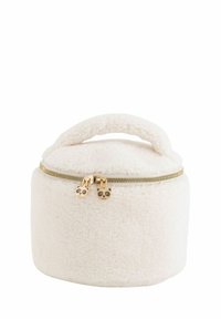 Rund, cremefarvet taske lavet af blødt, tekstureret stof med en gylden lynlås og lynlåstrækformet som en panda. Har et topgreb til at bære.