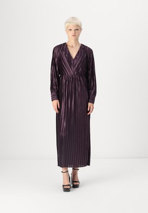 Long, purple dress made of pleated material with a deep V-neck and long sleeves. Worn with black platform heels. Smooth texture with vertical lines.