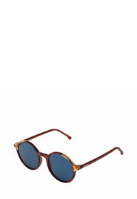 Lunettes de soleil rondes avec des verres bleu foncé, une monture bordeaux et des accents orange sur le dessus. Branches en métal fines ; finition lisse et brillante.