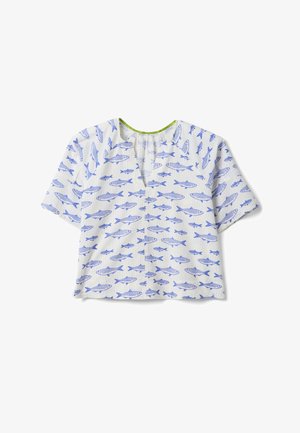 Blusa bianca a manica corta con motivo di pesci blu, scollo a V e scollatura arricciata con bordatura verde, stesa su sfondo bianco.