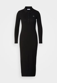 Robe polo noire à manches longues avec col et boutons, coupe ajustée, avec un petit logo crocodile vert sur le côté gauche de la poitrine.