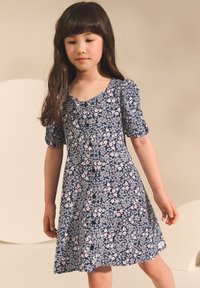 Vestito floreale blu navy con maniche corte a sbuffo, caratterizzato da dettagli con bottoni e una gonna svasata. Il tessuto presenta un motivo di piccoli fiori delicati.