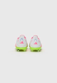 White soccer cleats with pink accents and green soles. Features a textured upper and three stripes logo on each heel. Transparent studs.