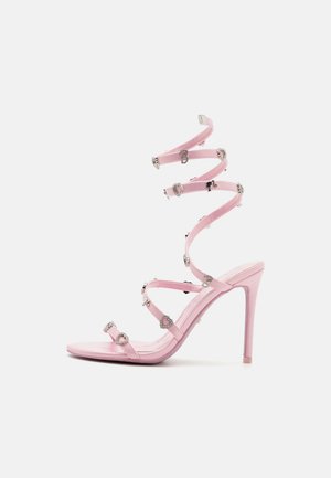 Rosa High-Heels-Sandalen mit schlankem Design, ausgestattet mit spiralförmigen Riemen, die mit herzförmigen Beschlägen und diamantähnlichen Akzenten verziert sind.