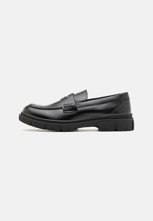 Black leather loafer with a wide strap across the vamp, rubber sole with thick treads, and smooth texture. Classic, sleek design.