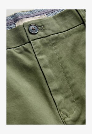 Olivgrüne Hose mit Knopfverschluss, aus glattem Baumwollstoff und einer subtilen Textur, mit kontrastierendem Futter in einem blau-weißen Muster.