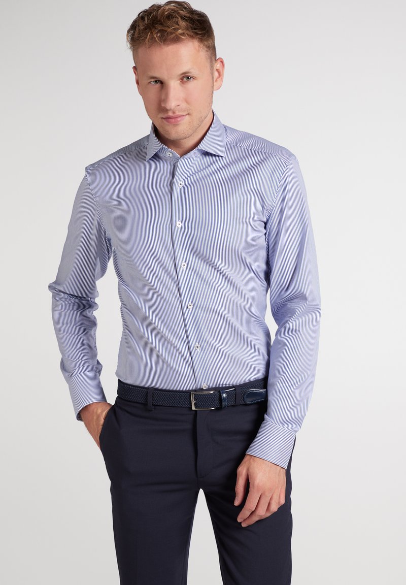 Gestreept overhemd in blauw en wit met een button-down kraag, lange mouwen en een getailleerd ontwerp, gecombineerd met donkere broek en een gestructureerde riem.