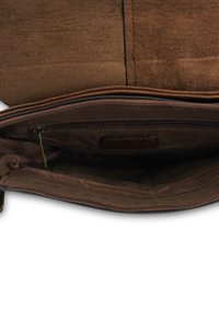 Wnętrze brązowej torebki z zamszu z zamykaną na zamek kieszenią, gładkim wykończeniem i małą skórzaną metką. Prosty design i funkcjonalny układ.
