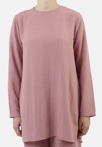Top a manica lunga in morbido tessuto rosa texturizzato. Collo rotondo, vestibilità rilassata e orlo posteriore più lungo. Design semplice senza hardware visibile o motivi.