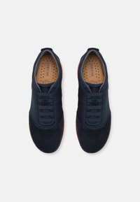 Navy blue sneakers with a combination of smooth and textured materials, featuring elastic laces and an orange rubber sole. Geox branding visible.