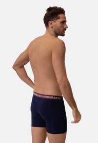Navy blue boxer shorts with a maroon elastic waistband featuring the word "ENDURANCE" in white. Made of smooth, stretchy fabric.
