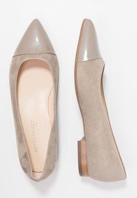Ballerines en daim beige avec un orteil pointu et un cap en vernis brillant. Texture lisse avec un petit talon carré et un logo discret sur la semelle intérieure.