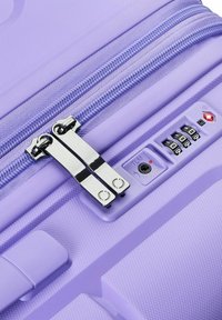 Valigia rigida viola con zip argentata, lucchetto a combinazione e finitura testurizzata per una migliore presa e durata.