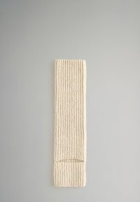 Pletený žebrovaný čelenka v krémové barvě. Měkká textura, obdélníkový tvar a složené konce. Vhodná pro nošení v chladném počasí.