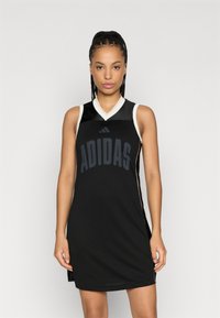 Vestito da basket nero senza maniche con spacchi laterali, caratterizzato da una texture in rete e rifiniture bianche. Grande logo "ADIDAS" sul davanti in blu scuro.