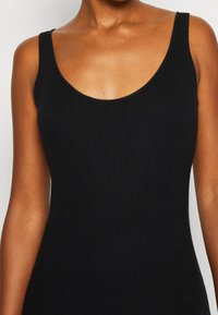 Czarny prążkowany top na ramiączkach z dekoltem na okrągło i cienkimi paskami na ramionach, wykonany z miękkiego, elastycznego materiału dla wygody.