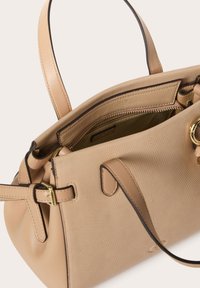 Borsa a mano in pelle beige con finitura testurizzata, interno con cerniera e doppi manici; presenta hardware dorato e accenti neri a contrasto.