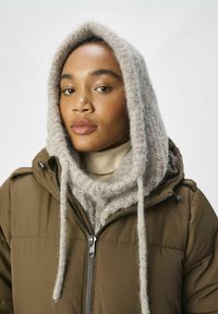 Doudoune marron avec zip, dotée d'une écharpe à capuchon en tricot gris clair. L'écharpe a une finition douce et texturée et pend de manière lâche.