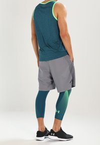 Mörkblå linne med gröna detaljer, grå shorts och mörkblå leggings med prickigt mönster. Svarta löparskor kompletterar outfiten.