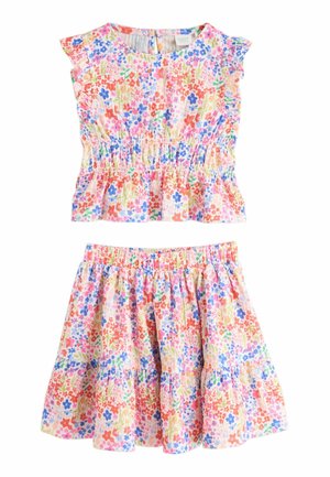 Floral two-piece set featuring a smocked bodice top and tiered skirt. Light pink background adorned with multicolored flowers and ruffled sleeves.