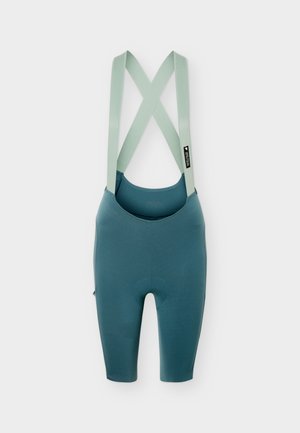 Blue cycling bib shorts with light green crossed shoulder straps and a small black label on the right strap against a white background.