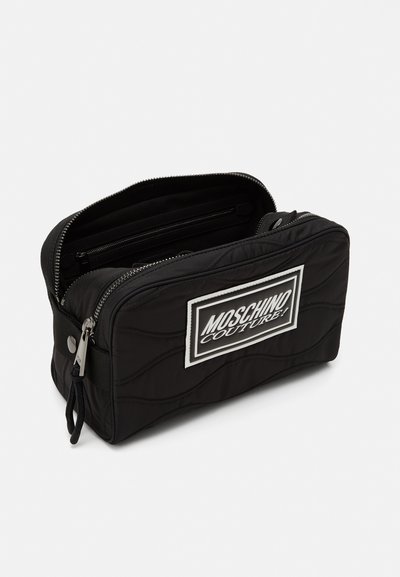 Geantă cosmetică neagră, matlasată, cu un patch alb cu logo, închidere cu fermoar și compartimente interioare. Fabricată din nailon cu o textură netedă.