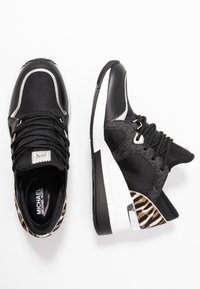 Černé sportovní tenisky kombinující texturovanou látku a kůži, bílá podrážka a akcent s leopardím potiskem na patě.