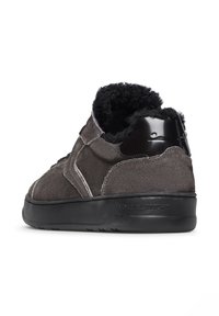 Sneaker in suede grigio con fodera in pelliccia nera morbida, cappuccio del tallone nero lucido, dettagli di cucitura bianchi e suola in gomma testurizzata. Logo del marchio visibile.