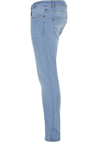 Vékony farmernadrág világoskék denim anyagból, közepes magasságú derékkal, öt zsebbel, enyhe kopásokkal és sima textúrával.