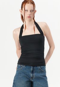 Zwarte haltertop met een vierkante halslijn, geplooide textuur en slim fit, gecombineerd met hoge blauwe denim shorts.