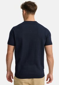 Granatowy sweter z krótkim rękawem, wykonany z dzianiny, z wąskim ściągaczem przy szyi i mankietach, gładką fakturą oraz prostym wykończeniem dołu.