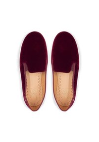 Bordeaux fluwelen instapschoenen met een gladde textuur, ronde neus en subtiele perforaties op een tankleurige binnenzool. Minimalistisch ontwerp, zonder hardware.